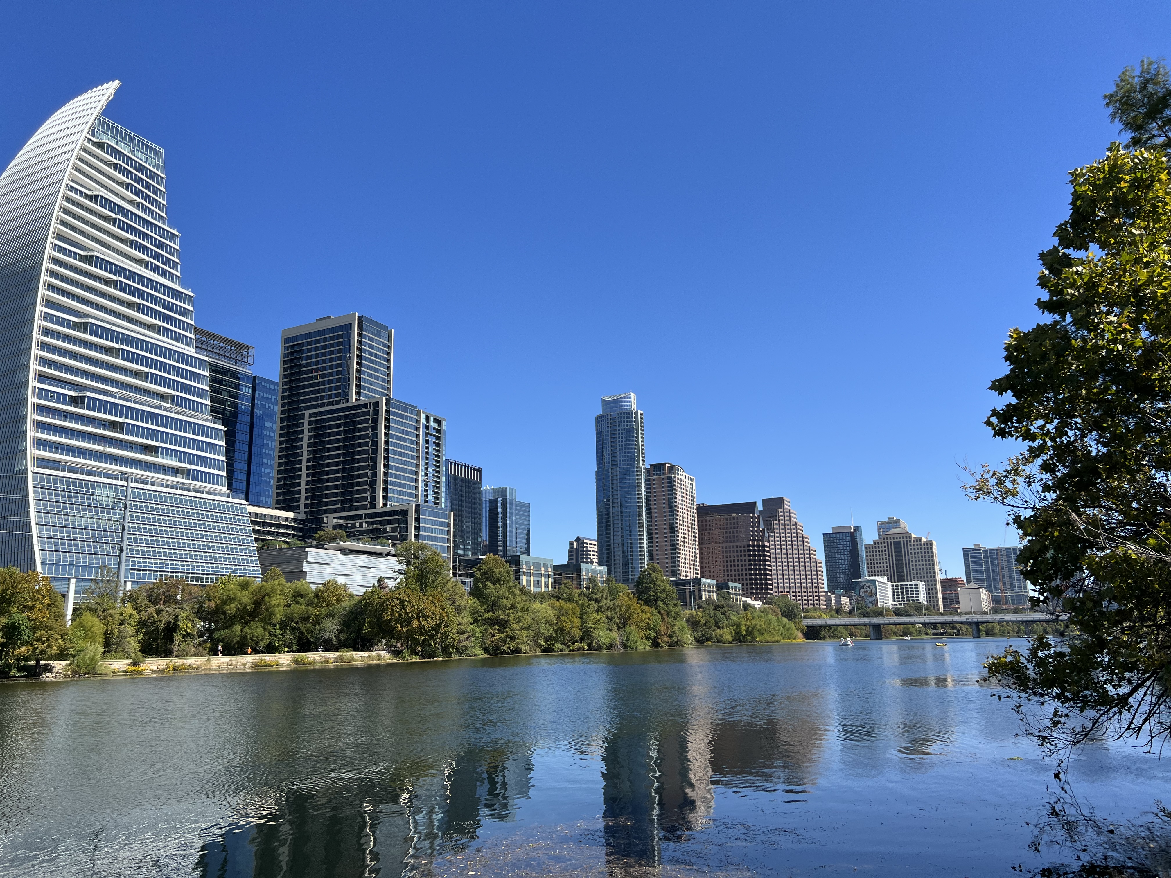 Lady Bird Lake with trees along the water and the downtown Austin skyline